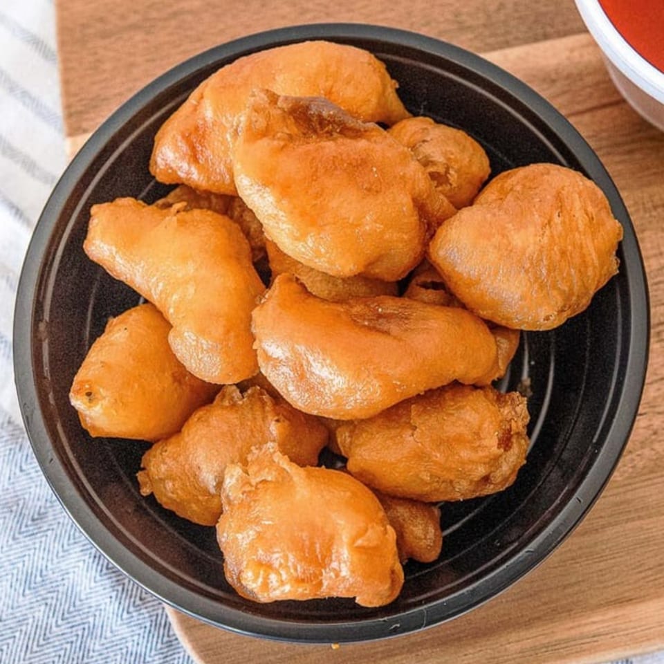 A black bowl filled with golden-brown, crispy fried chicken pieces from GOLDEN STAR.