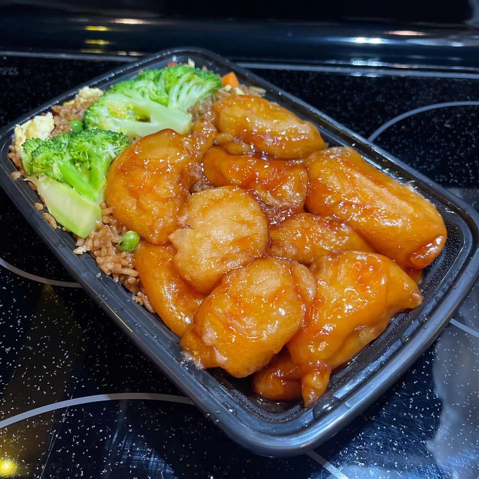 Golden Star's orange chicken with fried rice and broccoli in a black takeout container.